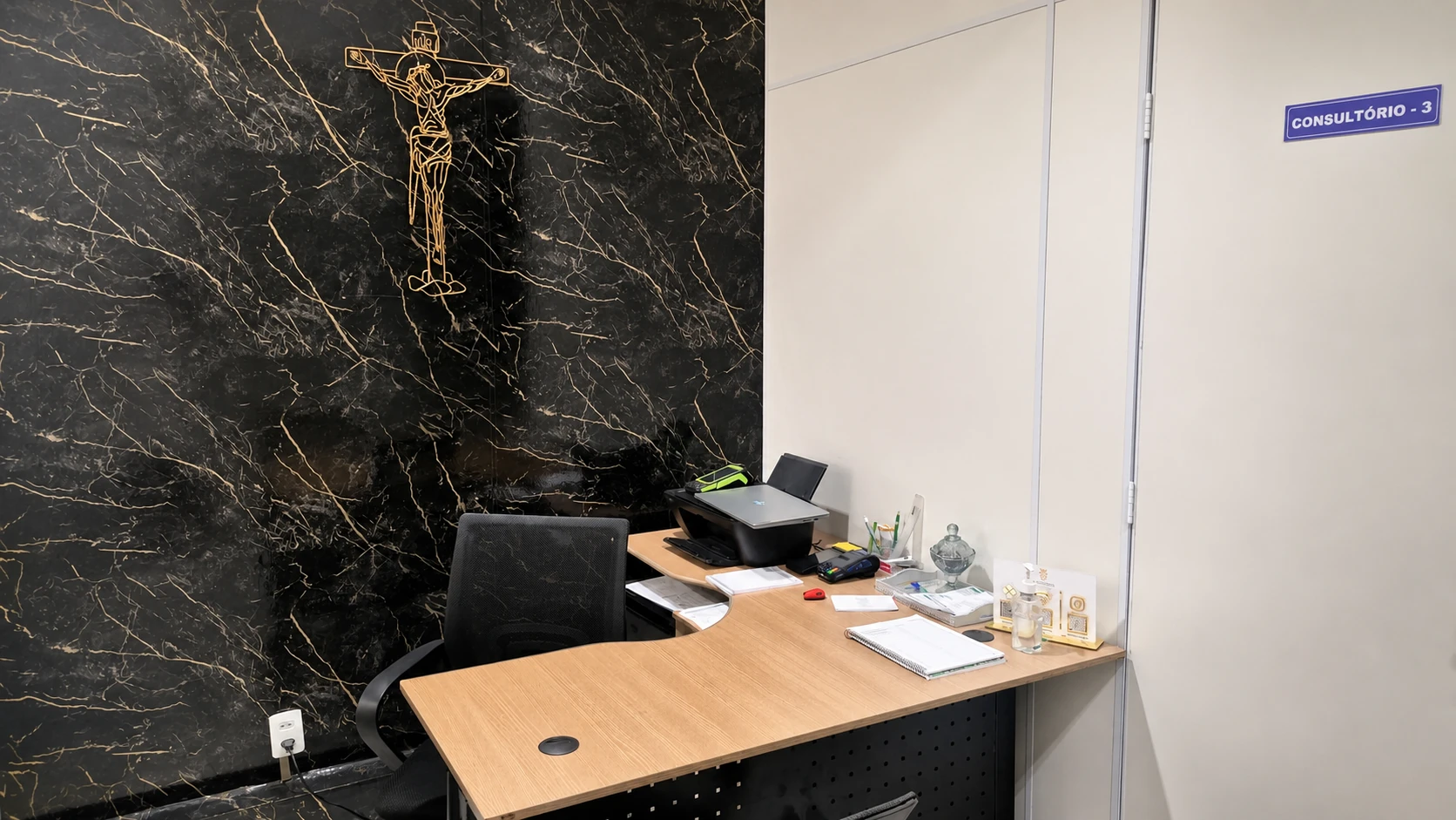 Consultório 03 da Odonto Plus com mesa de atendimento e parede de mármore escuro